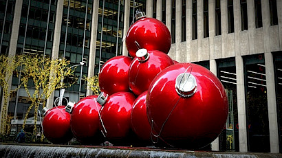 Gian Christmas tree balls, shiny red, as a sculpture, piled in a small pull on a New York City square