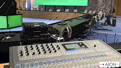 Soundcraft mixing console at a conference, with the speakers’ microphones on the table beyond